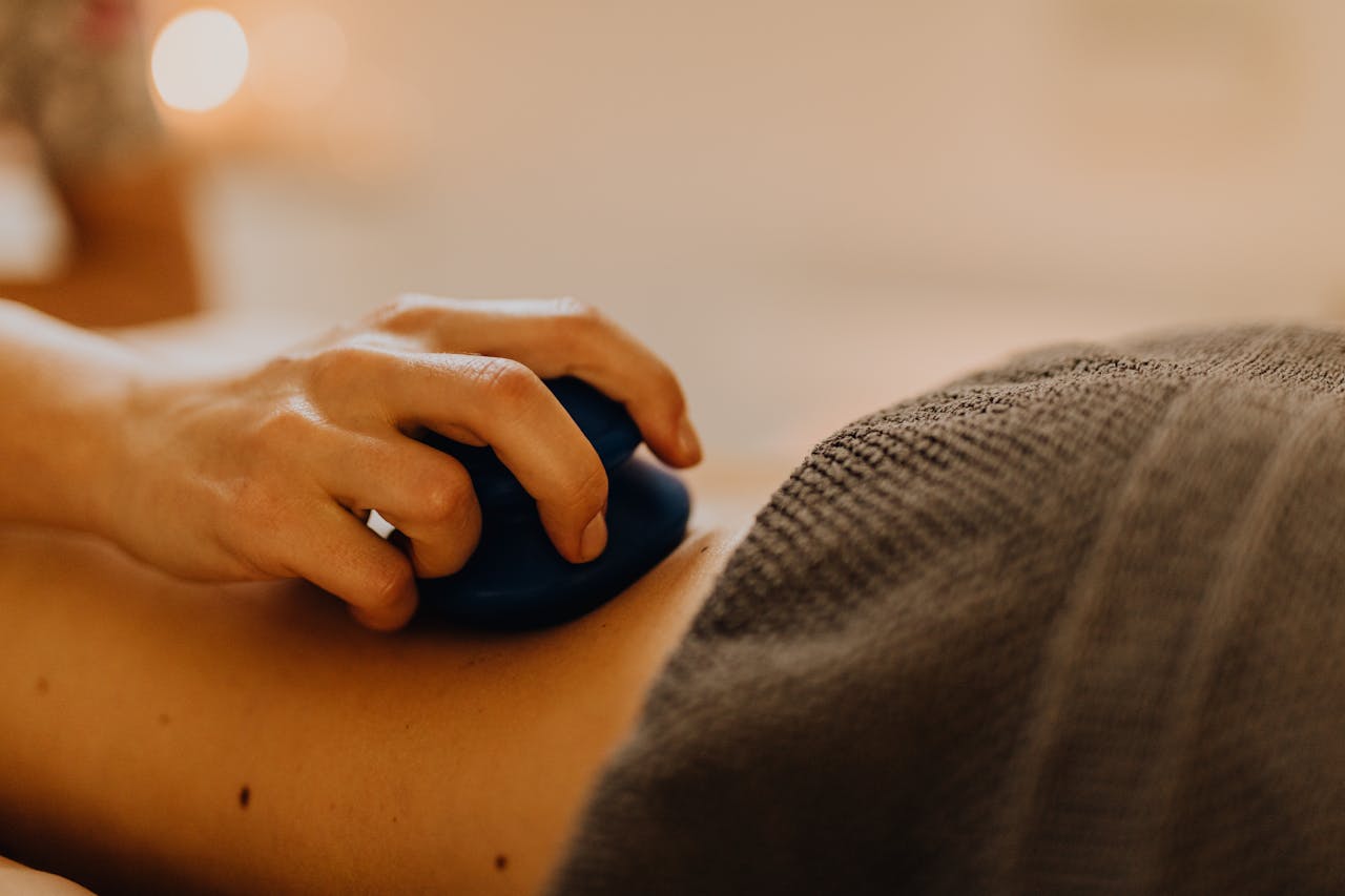Hands applying relaxing massage therapy with hot stones in a calming spa environment.